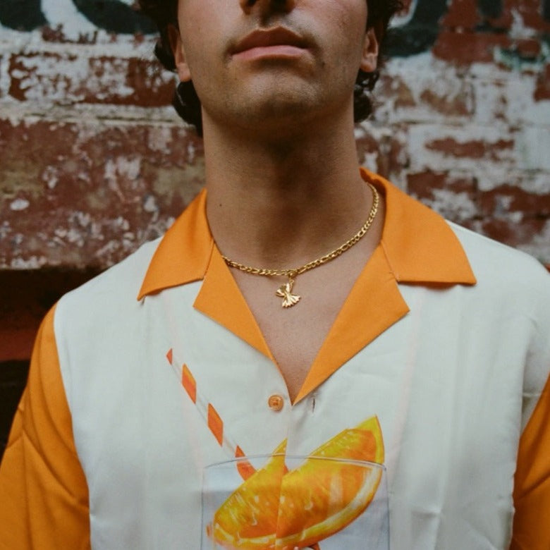Man wearing chunky gold chain necklace with farfalle charm