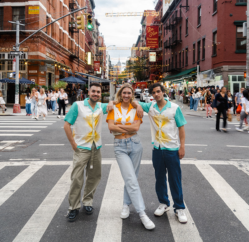 2 guys and a girl standing in the middle of the road in Little Italy. They are wearing shirts with Spritzes and farfalle pasta on them 